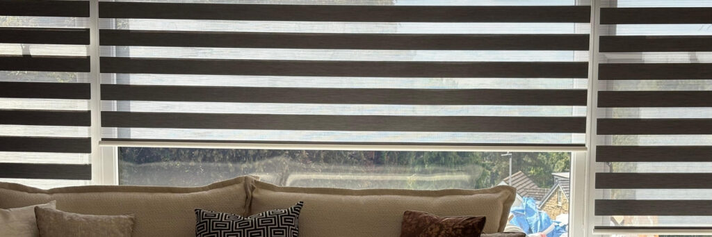 Zebra blinds lowered over a window behind a cushioned sofa