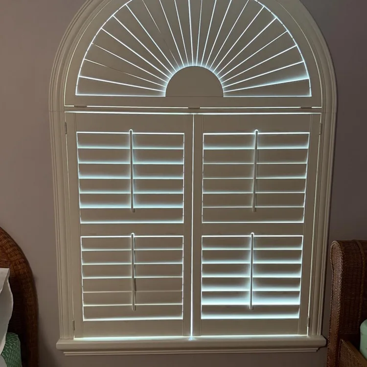 Custom plantation shutters with a matching sunburst panel on an arched window