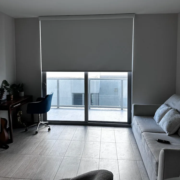 Gray roller shade lowered over a sliding glass door